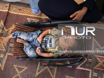 Palestinian infant Abdul Rahman Abu Al-Jidyan, 11, who contracts polio, receives care from his mother and family inside a tent in a shelter...