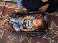 Palestinian infant Abdul Rahman Abu Al-Jidyan, 11, who contracts polio, receives care from his mother and family inside a tent in a shelter...