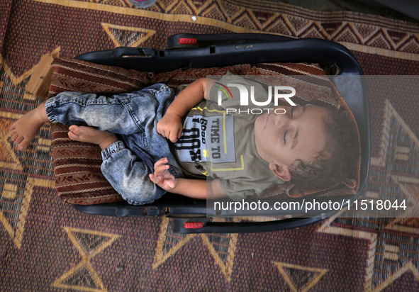 Palestinian infant Abdul Rahman Abu Al-Jidyan, 11, who contracts polio, receives care from his mother and family inside a tent in a shelter...