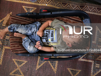 Palestinian infant Abdul Rahman Abu Al-Jidyan, 11, who contracts polio, receives care from his mother and family inside a tent in a shelter...