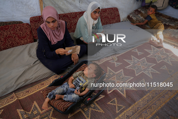 Palestinian infant Abdul Rahman Abu Al-Jidyan, 11, who contracts polio, receives care from his mother and family inside a tent in a shelter...