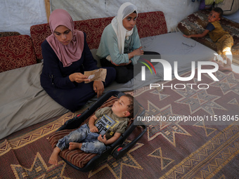 Palestinian infant Abdul Rahman Abu Al-Jidyan, 11, who contracts polio, receives care from his mother and family inside a tent in a shelter...