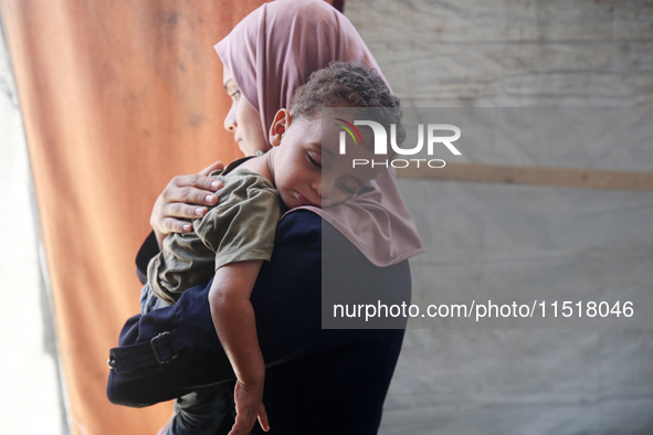 Palestinian infant Abdul Rahman Abu Al-Jidyan, 11, who contracts polio, receives care from his mother and family inside a tent in a shelter...