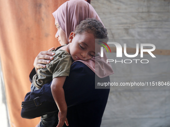 Palestinian infant Abdul Rahman Abu Al-Jidyan, 11, who contracts polio, receives care from his mother and family inside a tent in a shelter...