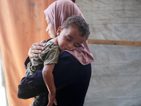 Palestinian infant Abdul Rahman Abu Al-Jidyan, 11, who contracts polio, receives care from his mother and family inside a tent in a shelter...