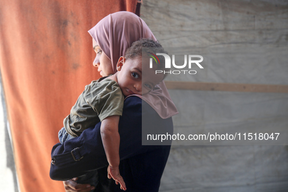 Palestinian infant Abdul Rahman Abu Al-Jidyan, 11, who contracts polio, receives care from his mother and family inside a tent in a shelter...