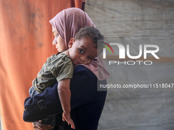 Palestinian infant Abdul Rahman Abu Al-Jidyan, 11, who contracts polio, receives care from his mother and family inside a tent in a shelter...