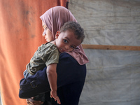 Palestinian infant Abdul Rahman Abu Al-Jidyan, 11, who contracts polio, receives care from his mother and family inside a tent in a shelter...