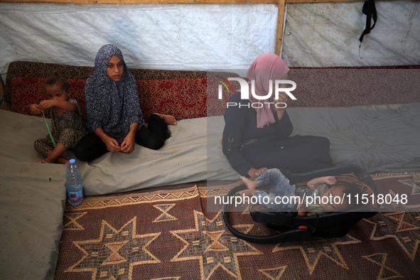 Palestinian infant Abdul Rahman Abu Al-Jidyan, 11, who contracts polio, receives care from his mother and family inside a tent in a shelter...