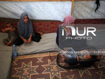 Palestinian infant Abdul Rahman Abu Al-Jidyan, 11, who contracts polio, receives care from his mother and family inside a tent in a shelter...