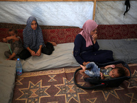 Palestinian infant Abdul Rahman Abu Al-Jidyan, 11, who contracts polio, receives care from his mother and family inside a tent in a shelter...