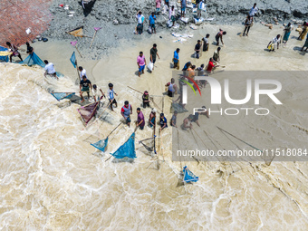 Fishermen and common people fish with handmade nets on the banks of the Feni River, ignoring the strong flow of floodwater along the Muhuri...