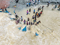 Fishermen and common people fish with handmade nets on the banks of the Feni River, ignoring the strong flow of floodwater along the Muhuri...