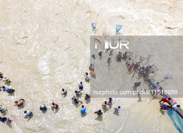 Fishermen and common people fish with handmade nets on the banks of the Feni River, ignoring the strong flow of floodwater along the Muhuri...