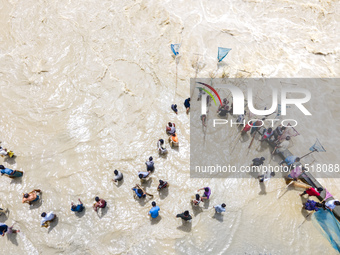 Fishermen and common people fish with handmade nets on the banks of the Feni River, ignoring the strong flow of floodwater along the Muhuri...