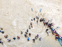 Fishermen and common people fish with handmade nets on the banks of the Feni River, ignoring the strong flow of floodwater along the Muhuri...