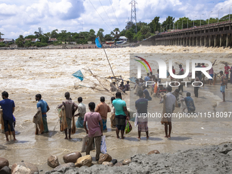 Fishermen and common people fish with handmade nets on the banks of the Feni River, ignoring the strong flow of floodwater along the Muhuri...