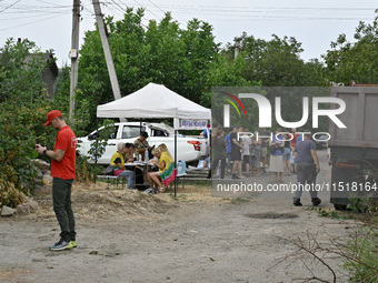 Locals accept aid after a Russian Shahed drone falls onto a residential area in Zaporizhzhia, Ukraine, on August 27, 2024. NO USE RUSSIA. NO...