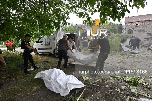 Men put the body of a victim in a human remains pouch into the van of undertakers during a response effort to a Russian Shahed drone collaps...