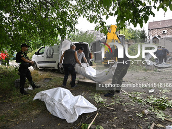 Men put the body of a victim in a human remains pouch into the van of undertakers during a response effort to a Russian Shahed drone collaps...