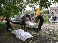 Men put the body of a victim in a human remains pouch into the van of undertakers during a response effort to a Russian Shahed drone collaps...