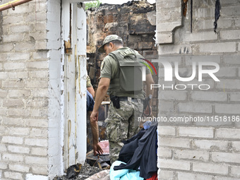 A law enforcer in a ballistic vest examines the ruins of a house destroyed after a Russian Shahed drone falls in a residential area in Zapor...