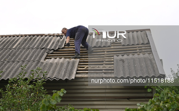 A man repairs the roof of a house destroyed after a Russian Shahed drone falls in a residential area in Zaporizhzhia, southeastern Ukraine,...