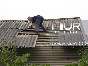 A man repairs the roof of a house destroyed after a Russian Shahed drone falls in a residential area in Zaporizhzhia, southeastern Ukraine,...