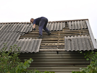 A man repairs the roof of a house destroyed after a Russian Shahed drone falls in a residential area in Zaporizhzhia, southeastern Ukraine,...