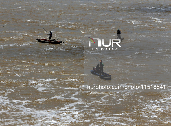 Villagers fish on their boat near the Chao Phraya Dam in Chai Nat province, north of Bangkok, on August 27, 2024. The dam releases water due...