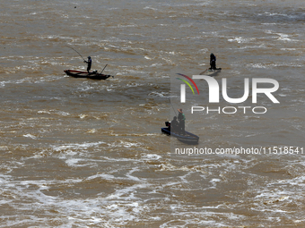 Villagers fish on their boat near the Chao Phraya Dam in Chai Nat province, north of Bangkok, on August 27, 2024. The dam releases water due...