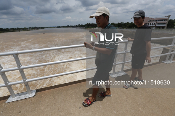 People watch as floodwaters are released from the Chao Phraya Dam in Chai Nat province, north of Bangkok, on August 27, 2024. The dam releas...