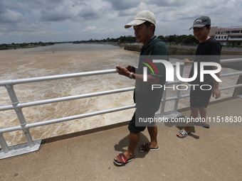 People watch as floodwaters are released from the Chao Phraya Dam in Chai Nat province, north of Bangkok, on August 27, 2024. The dam releas...