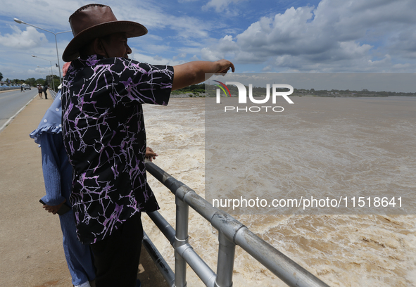 People watch as floodwaters are released from the Chao Phraya Dam in Chai Nat province, north of Bangkok, on August 27, 2024. The dam releas...