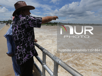 People watch as floodwaters are released from the Chao Phraya Dam in Chai Nat province, north of Bangkok, on August 27, 2024. The dam releas...