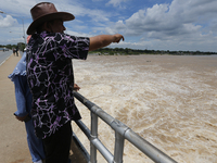 People watch as floodwaters are released from the Chao Phraya Dam in Chai Nat province, north of Bangkok, on August 27, 2024. The dam releas...