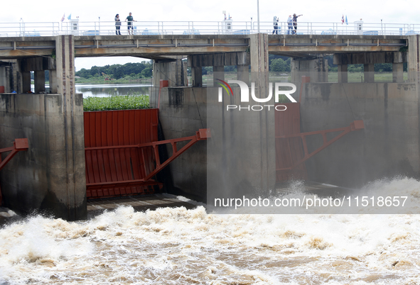 People watch as floodwaters are released from the Chao Phraya Dam in Chai Nat province, north of Bangkok, on August 27, 2024. The dam releas...