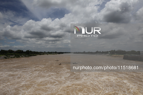 Villagers fish on their boat near the Chao Phraya Dam in Chai Nat province, north of Bangkok, on August 27, 2024. The dam releases water due...