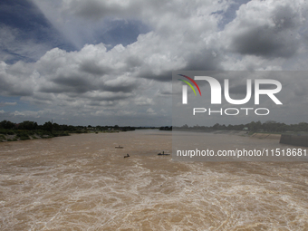 Villagers fish on their boat near the Chao Phraya Dam in Chai Nat province, north of Bangkok, on August 27, 2024. The dam releases water due...