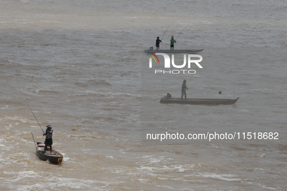 Villagers fish on their boat near the Chao Phraya Dam in Chai Nat province, north of Bangkok, on August 27, 2024. The dam releases water due...