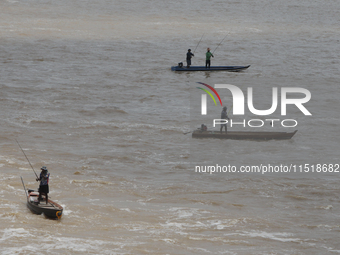 Villagers fish on their boat near the Chao Phraya Dam in Chai Nat province, north of Bangkok, on August 27, 2024. The dam releases water due...