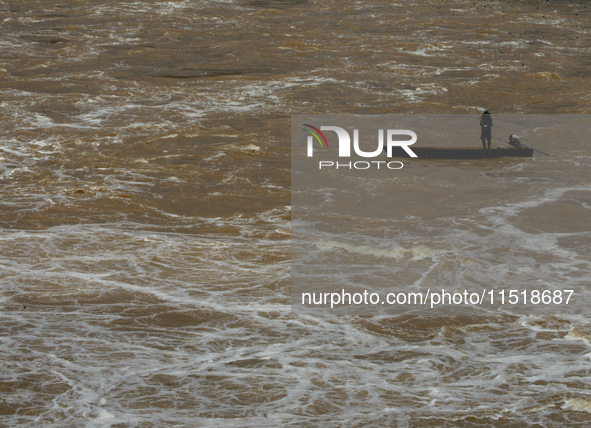 Villagers fish on their boat near the Chao Phraya Dam in Chai Nat province, north of Bangkok, on August 27, 2024. The dam releases water due...