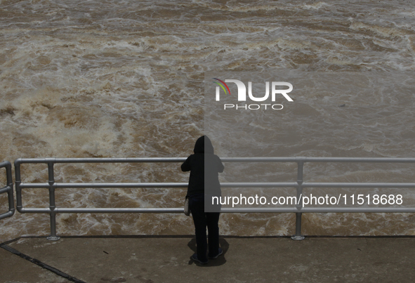 People watch as floodwaters are released from the Chao Phraya Dam in Chai Nat province, north of Bangkok, on August 27, 2024. The dam releas...