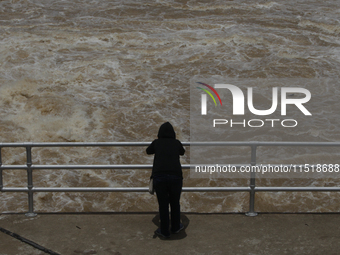 People watch as floodwaters are released from the Chao Phraya Dam in Chai Nat province, north of Bangkok, on August 27, 2024. The dam releas...