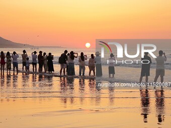 Tourists watch the sunrise at the Golden Beach in Qingdao, China, on August 28, 2024. (