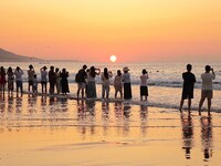 Tourists watch the sunrise at the Golden Beach in Qingdao, China, on August 28, 2024. (