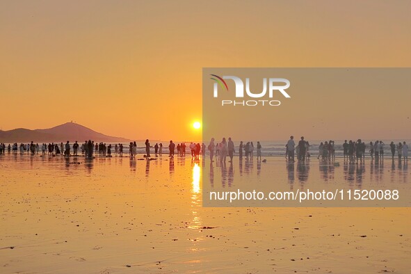 Tourists watch the sunrise at the Golden Beach in Qingdao, China, on August 28, 2024. 