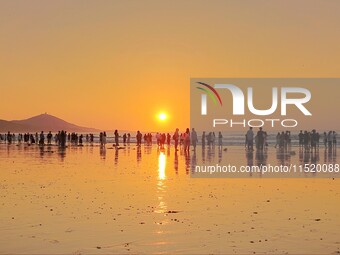 Tourists watch the sunrise at the Golden Beach in Qingdao, China, on August 28, 2024. (