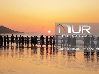 Tourists watch the sunrise at the Golden Beach in Qingdao, China, on August 28, 2024. (