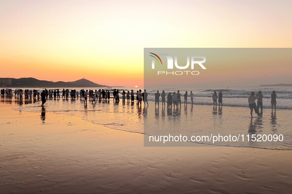 Tourists watch the sunrise at the Golden Beach in Qingdao, China, on August 28, 2024. 